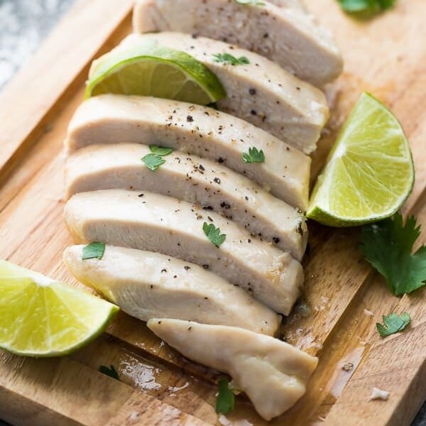 Sliced chicken on wood cutting board with cilantro lime chicken marinade and fresh limes