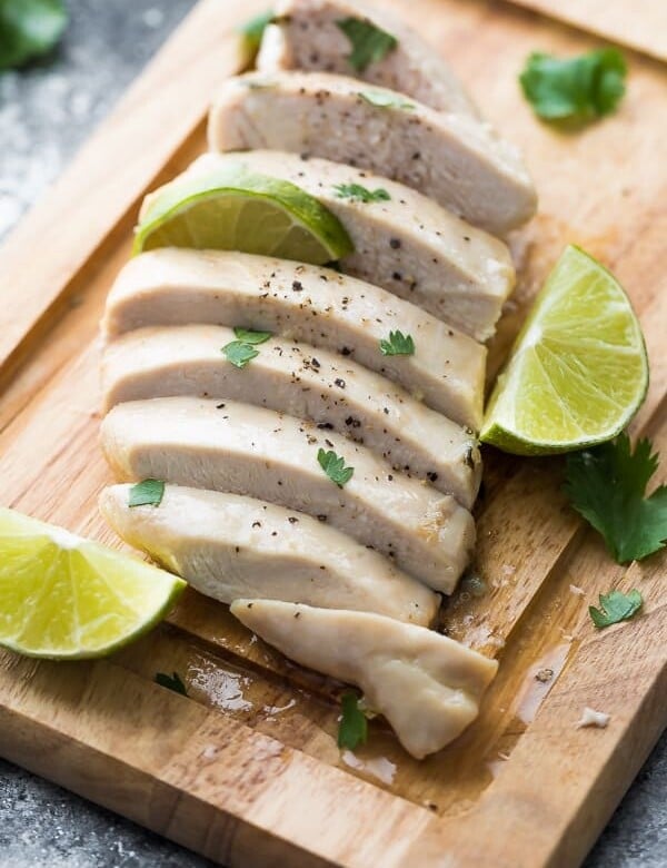 Sliced chicken on wood cutting board with cilantro lime chicken marinade and fresh limes