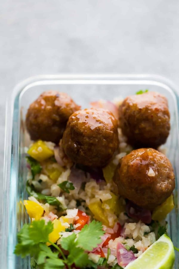 Close up view of glass meal prep container with honey chipotle meatballs and cilantro lime cauliflower rice