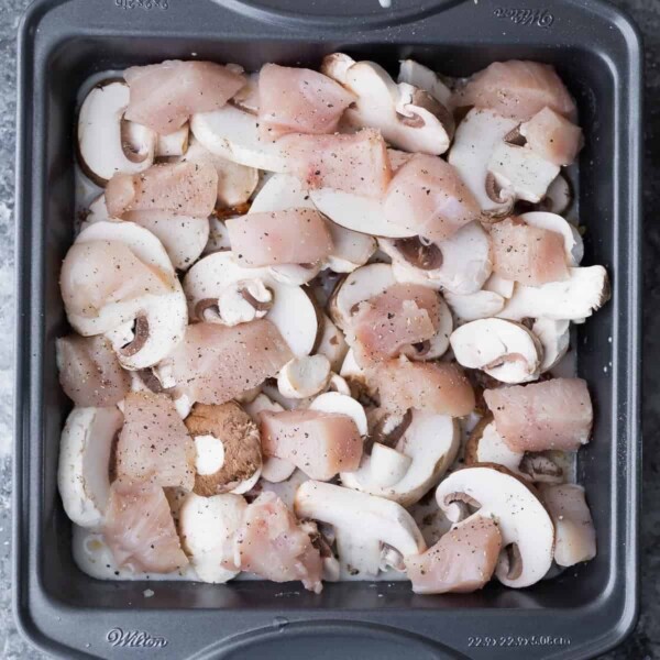 raw chicken and mushrooms in a baking pan before baking