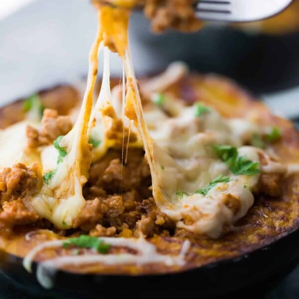 close up of taco stuffed acorn squash with fork taking out a bite of melted cheese