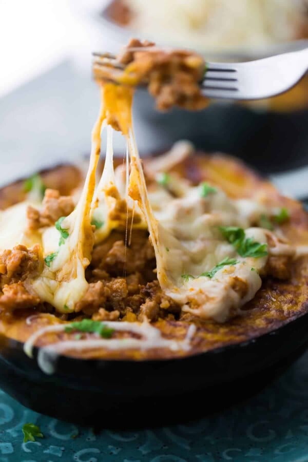 Side view of Taco stuffed acorn squash with cheese melting off a fork