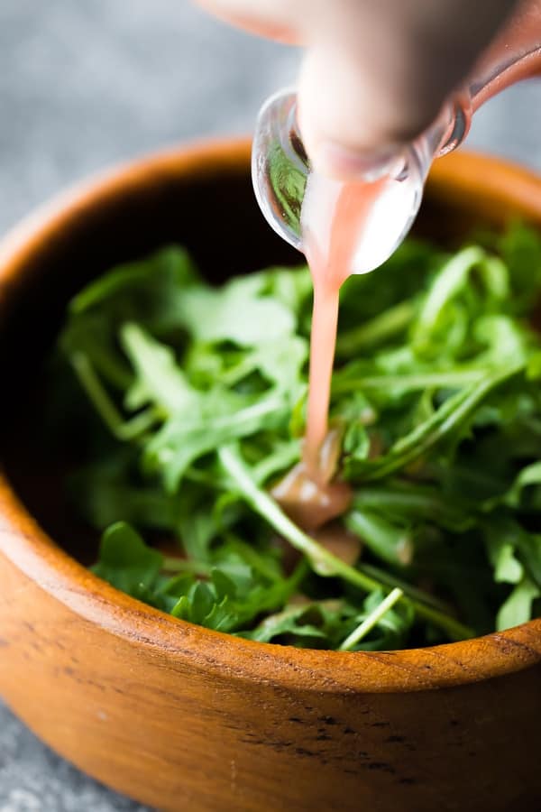 pouring dressing onto leafy salad