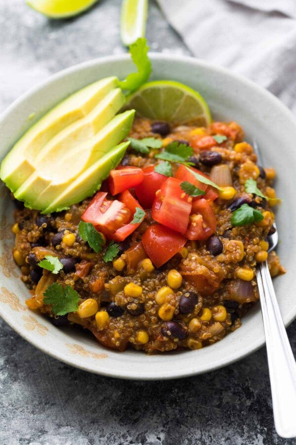 close up shot of Instant Pot enchilada quinoa casserole in bowl with avocado and tomatoes