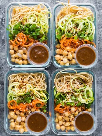 overhead shot of four meal prep containers with sesame noodles and spiralized vegetables