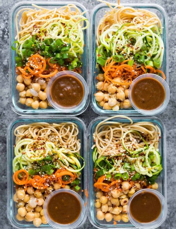 overhead shot of four meal prep containers with sesame noodles and spiralized vegetables