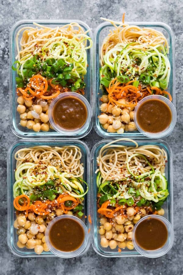 overhead shot of four meal prep containers with sesame noodles and spiralized vegetables