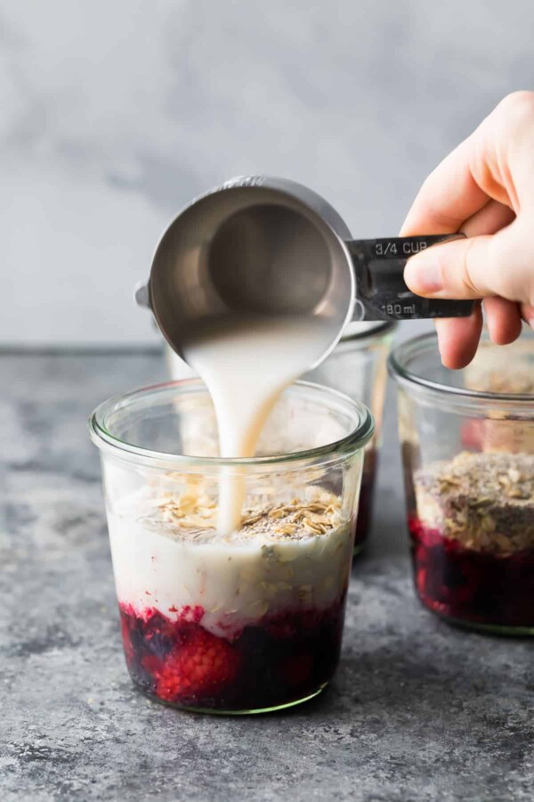 pouring almond milk into overnight oats jar