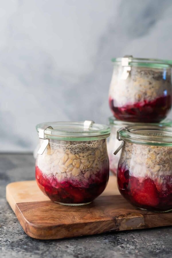 Four jars filled with overnight oats with fruit on the bottom