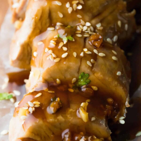 Close up shot of sliced instant pot pork tenderloin topped with soy ginger sauce and sesame seeds