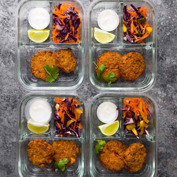 Make Ahead Thai Salmon Patties packed in four meal prep containers with salad, sauce, and lemon wedges