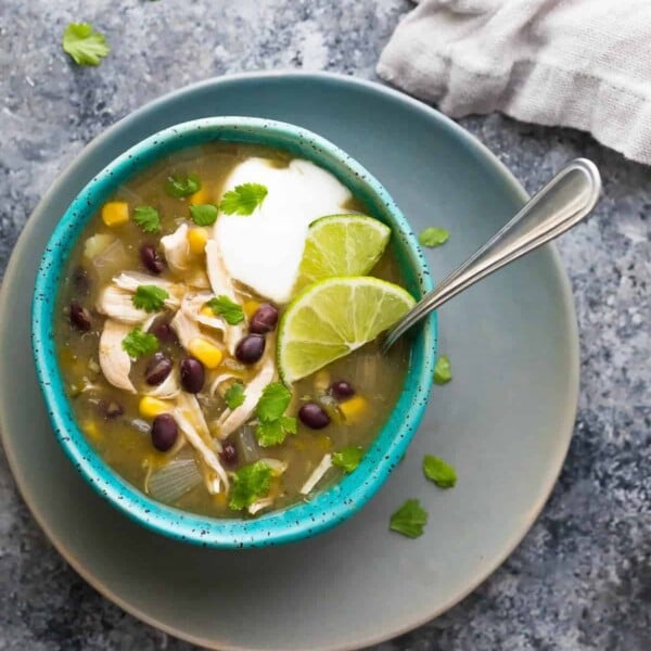 overhead shot of chicken chile verde soup in blue bowl with spoon on gray counter