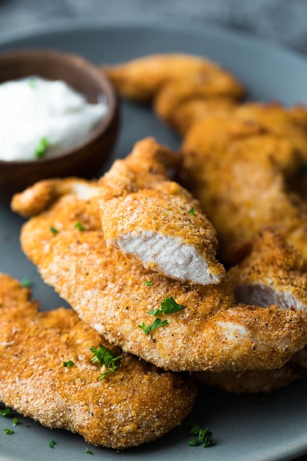 air fryer chicken tenders on a plate with one cut open