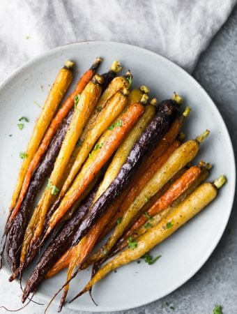 Multi-colored honey roasted carrots on a white plate
