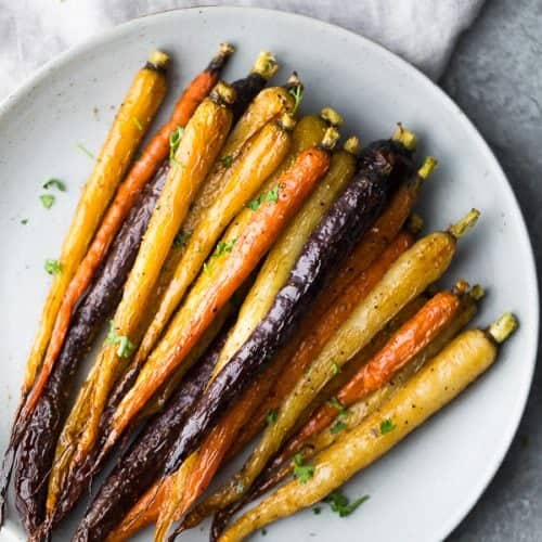 Multi-colored honey roasted carrots on a white plate
