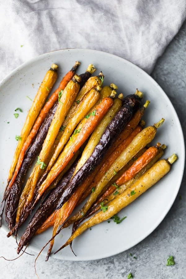 Multi-colored honey roasted carrots on a white plate