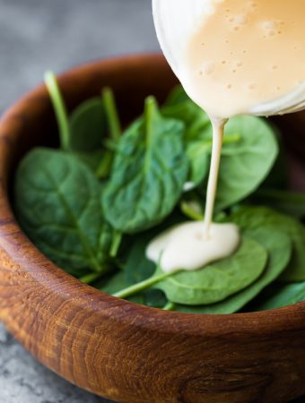 pouring maple tahini dressing onto a salad