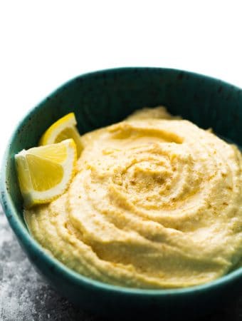 close up of a blue bowl filled with hummus and lemon slices