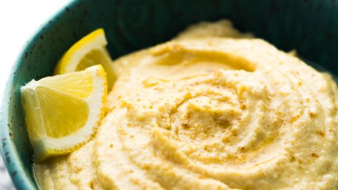 close up of a blue bowl filled with hummus and lemon slices