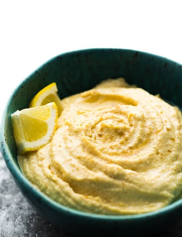 close up of a blue bowl filled with hummus and lemon slices