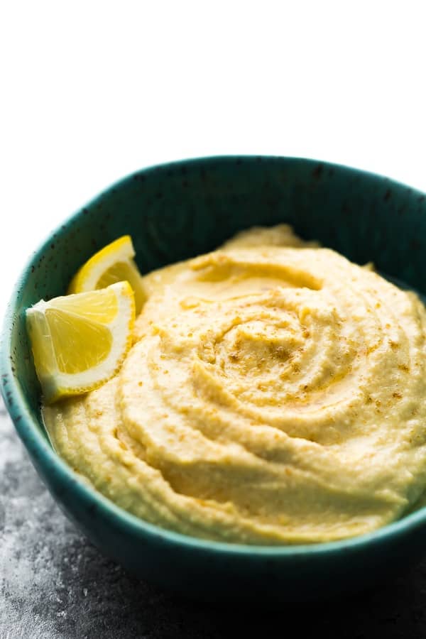 homemade hummus in blue bowl with lemon wedges