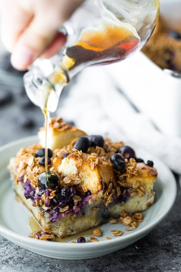 pouring maple syrup onto the blueberry overnight french toast bake