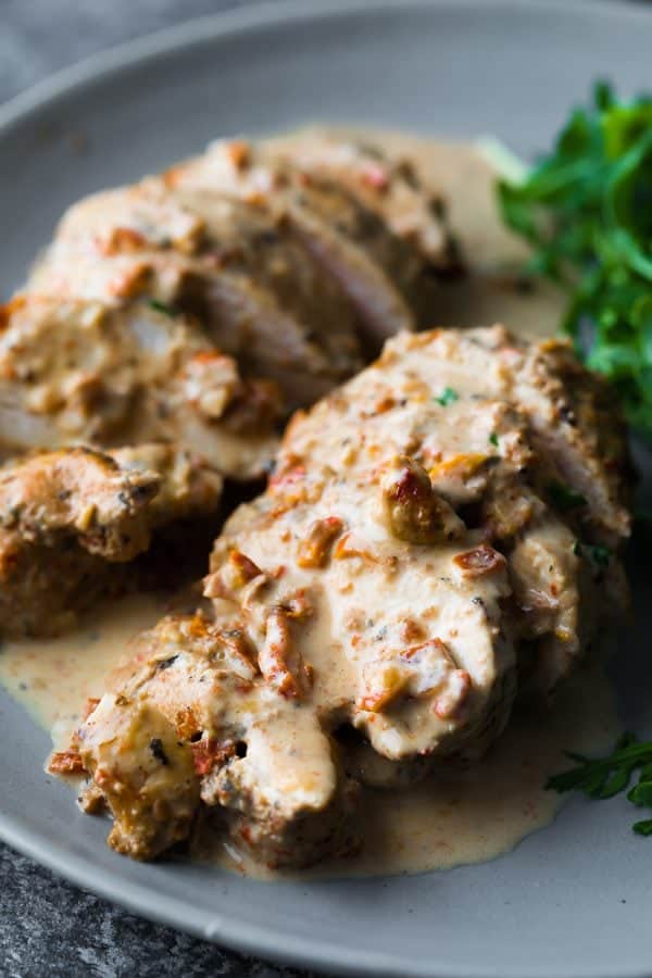 close up shot of chicken breasts sliced with sun dried tomato cream sauce