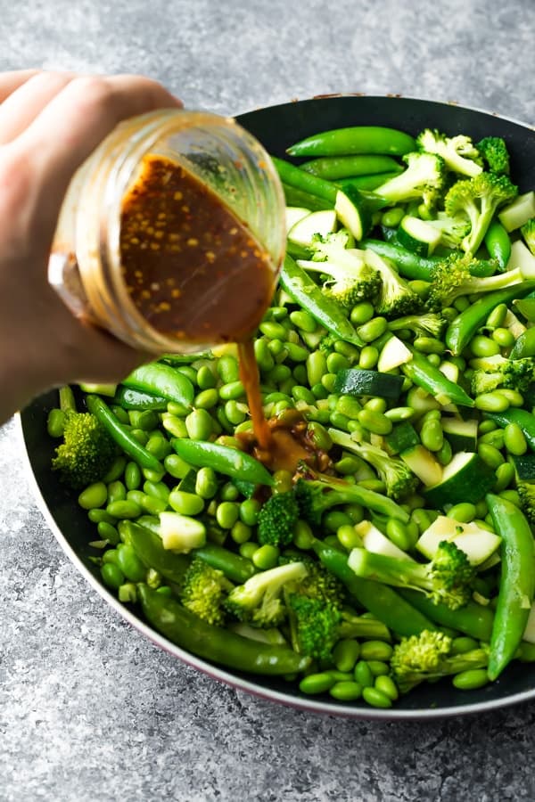 pouring the vegan teriyaki sauce onto the stir fry