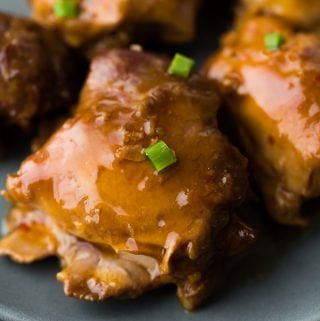 close up shot of sticky honey garlic chicken thighs on gray plate