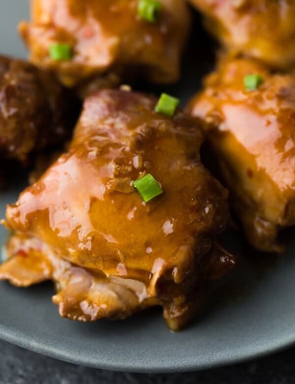 close up shot of sticky honey garlic chicken thighs on gray plate