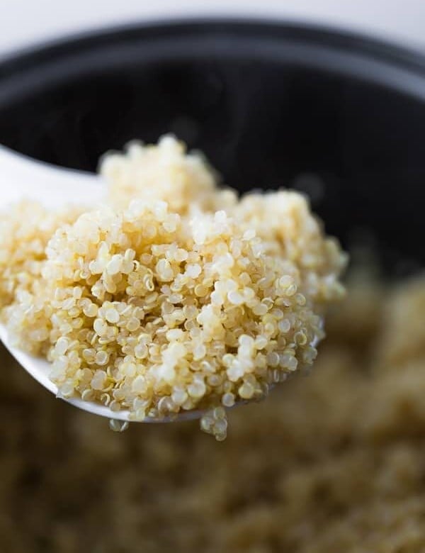 white spoon with a bite of quinoa cooked in the rice cooker