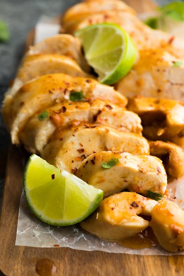 close up shot of Chipotle Lime Chicken Breasts sliced on parchment paper with lime wedges