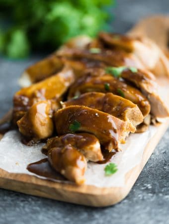 Close up shot of soy ginger chicken sliced on wood cutting board