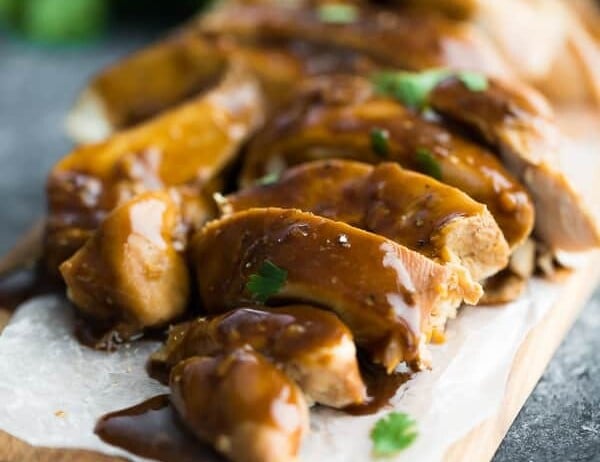 Close up shot of soy ginger chicken sliced on wood cutting board