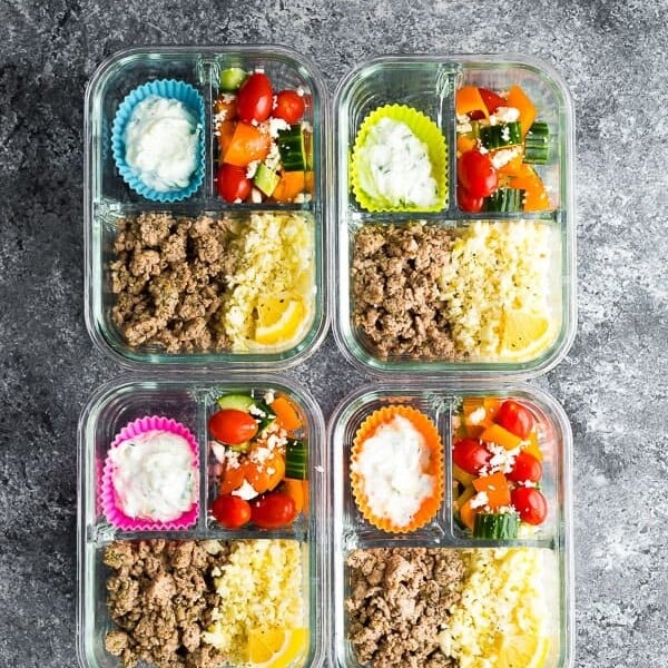 overhead shot of four meal prep containers with greek turkey and salad