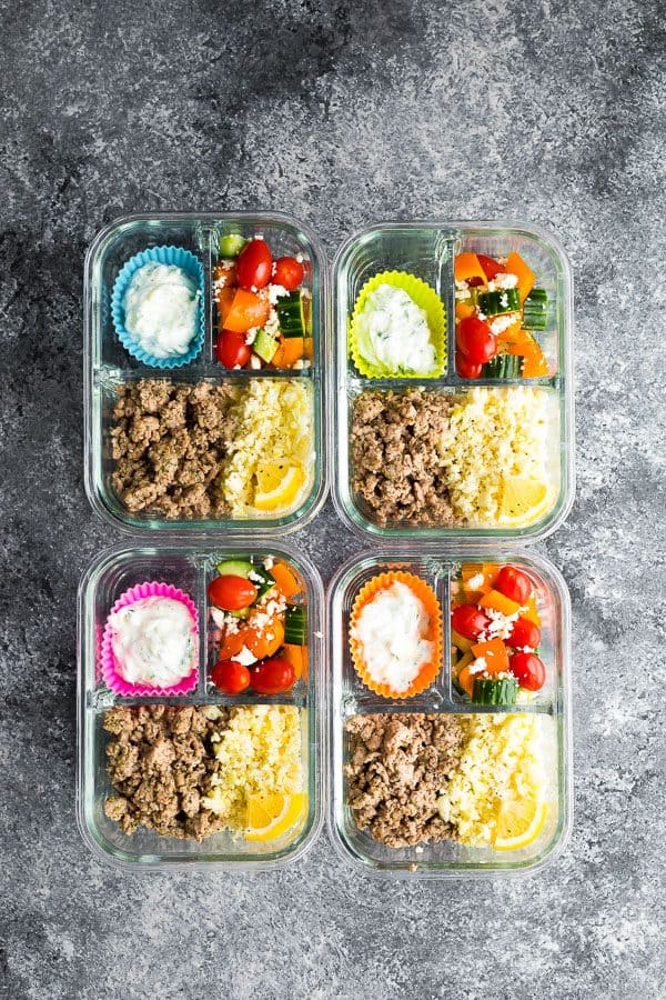 overhead shot of four meal prep containers with greek turkey and salad