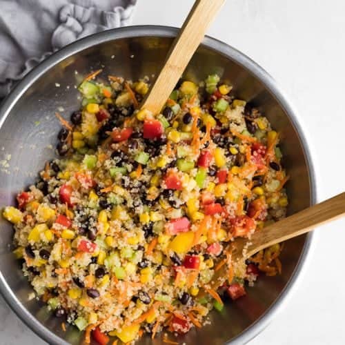 Quinoa Black Bean Salad in a large bowl with two wooden tongs