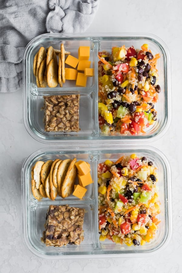 quinoa black bean salad in meal prep container with snack bar and crackers