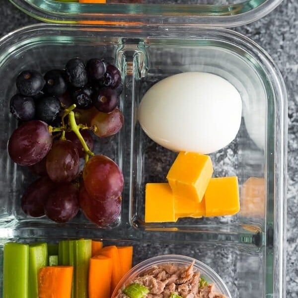 tuna protein bistro box in glass meal prep container including grapes, egg, cheese, and veggie sticks