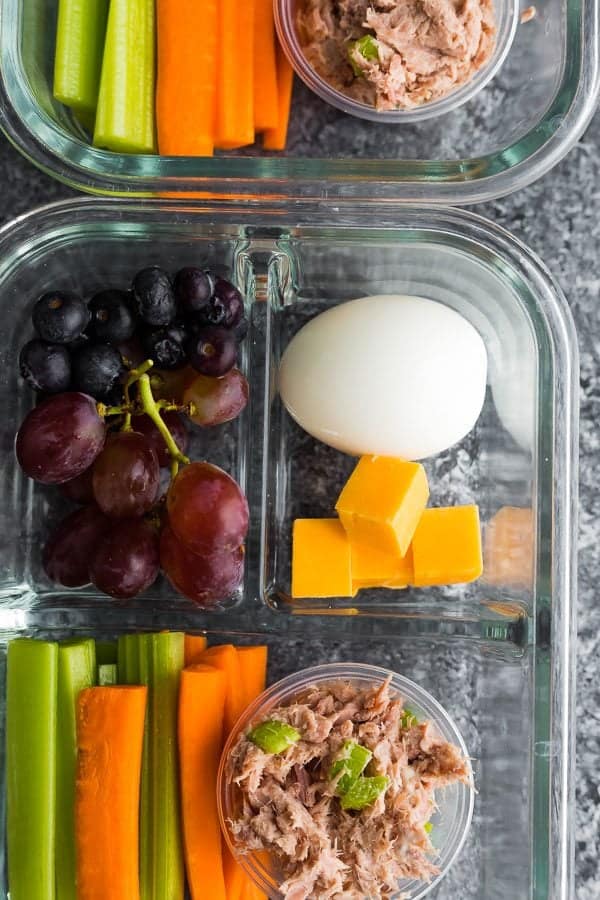 Üzüm, yumurta, peynir ve sebze çubukları dahil cam yemek hazırlama kabında ton balığı proteini bistro kutusu