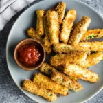 overhead shot of air fryer zucchini fries on gray plate with ketchup