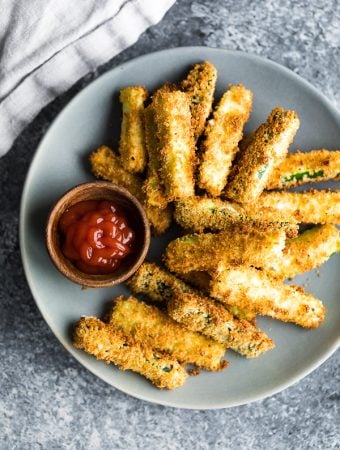 overhead shot of air fryer zucchini fries on gray plate with ketchup