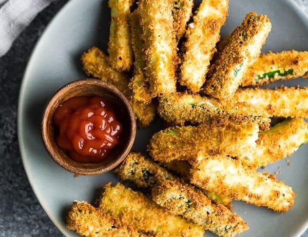 overhead shot of air fryer zucchini fries on gray plate with ketchup