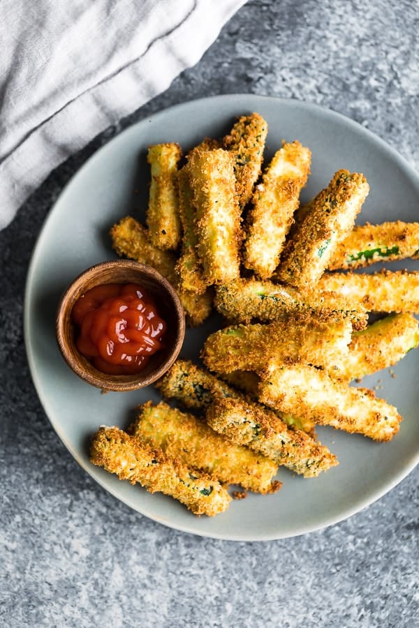 overhead shot of air fryer zucchini fries on gray plate with ketchup