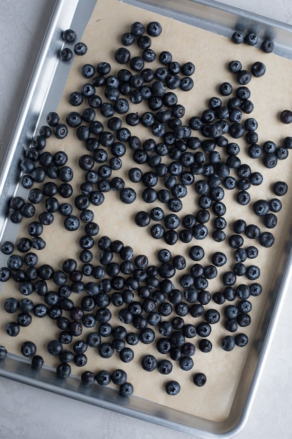 overhead shot of blueberries on a parchment lined baking sheet