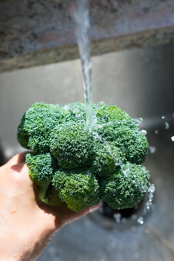 hand holding a head of broccoli under running water