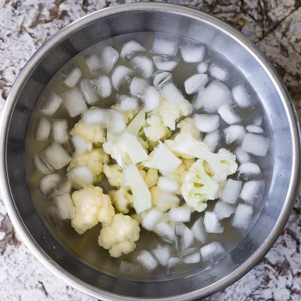 overhead shot of cauliflower florets in an ice bath