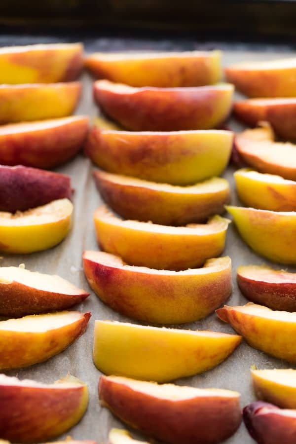 How to Freeze Peaches: peaches sliced and arranged on baking sheet