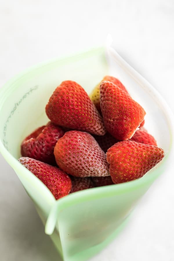 transferring frozen strawberries to silicone freezer bag