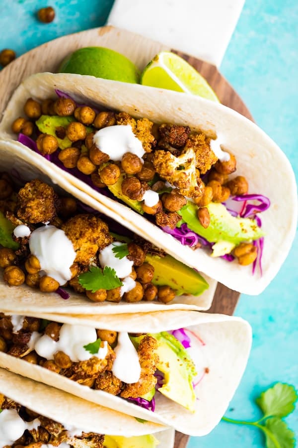 Close up of Air Fryer Cauliflower Chickpea Tacos on cutting board with blue background